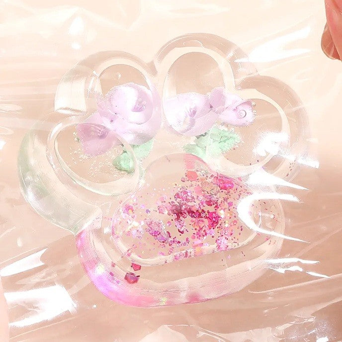 Jucarie Antistres Squishy, Labuta de Pisica Pufoasa cu Revenire Lenta si Insertii Flori, Material TPR Moale, 7 x 6.5 cm, Transparent Multicolor