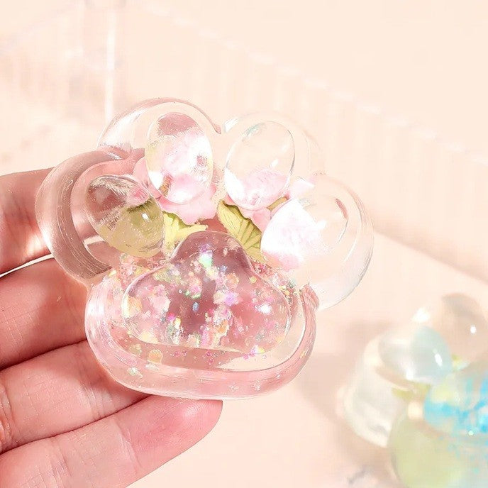 Jucarie Antistres Squishy, Labuta de Pisica Pufoasa cu Revenire Lenta si Insertii Flori, Material TPR Moale, 7 x 6.5 cm, Transparent Multicolor