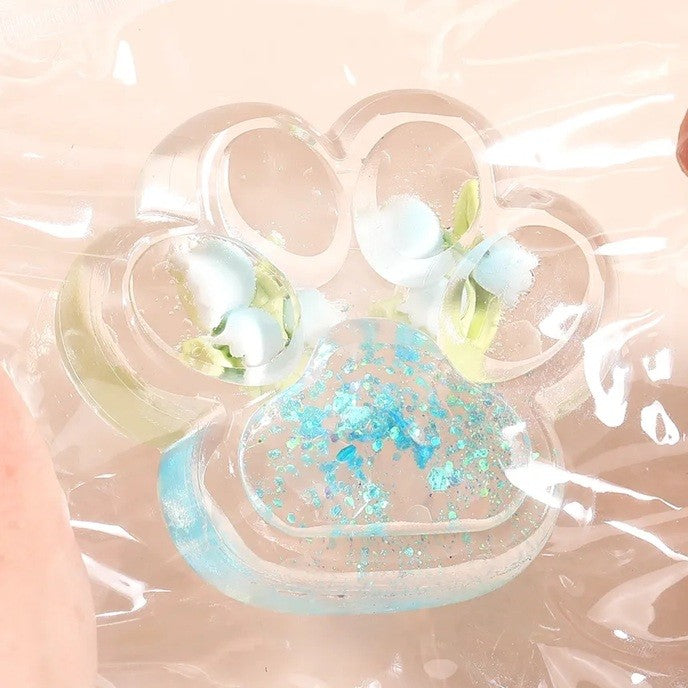 Jucarie Antistres Squishy, Labuta de Pisica Pufoasa cu Revenire Lenta si Insertii Flori, Material TPR Moale, 7 x 6.5 cm, Transparent Multicolor